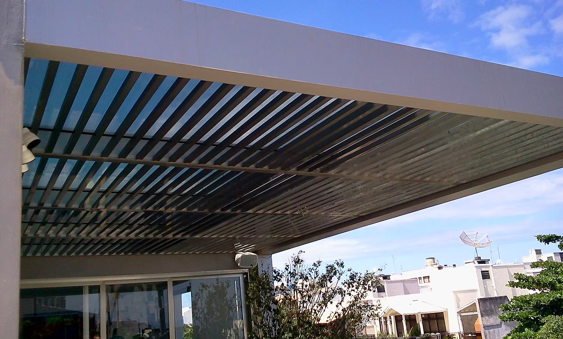 Cobertura com brises de alumínio horizontais sobre varanda de cobertura, em dia de céu azul