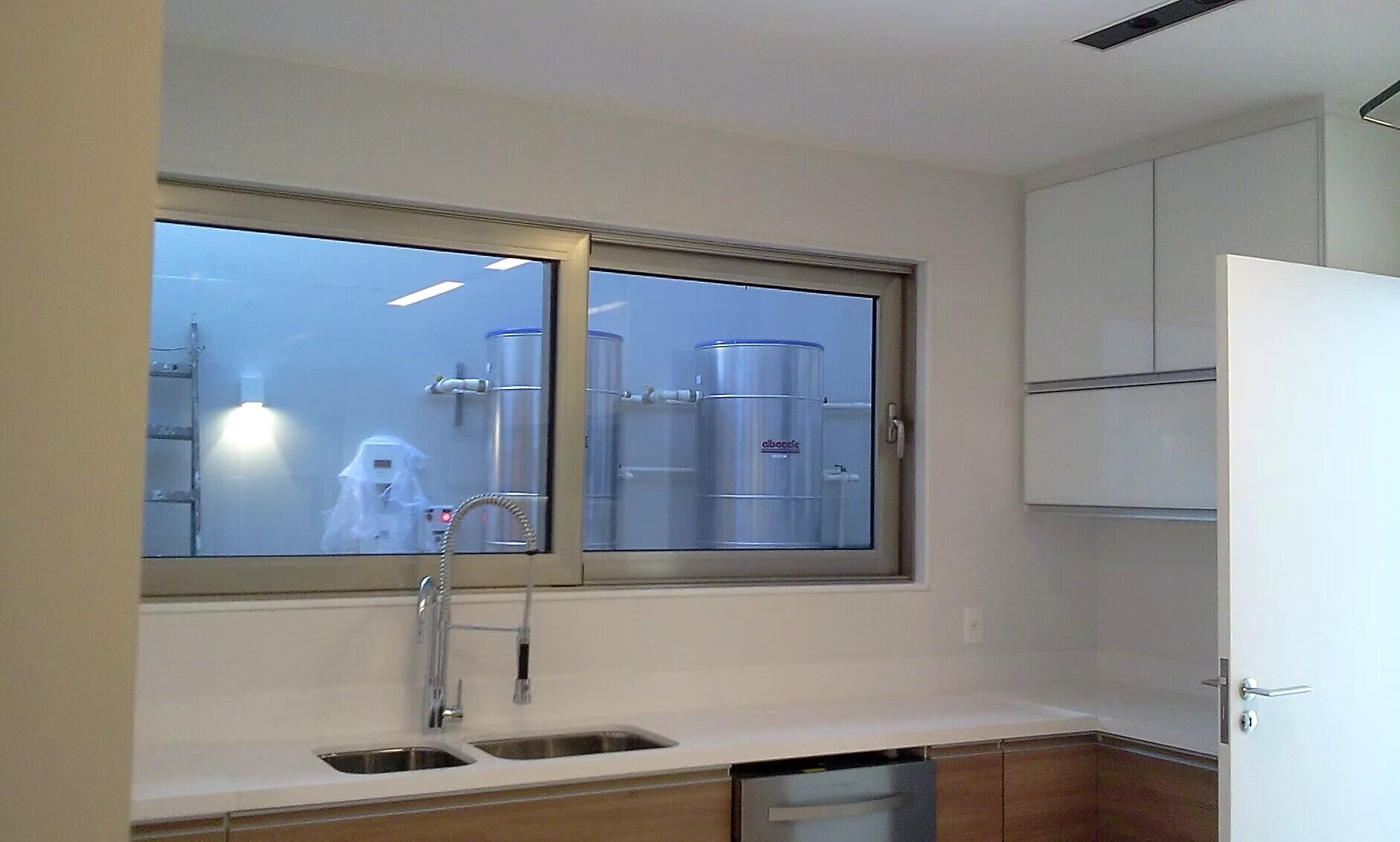 Janela acústica entre cozinha e área técnica com isolamento de equipamentos