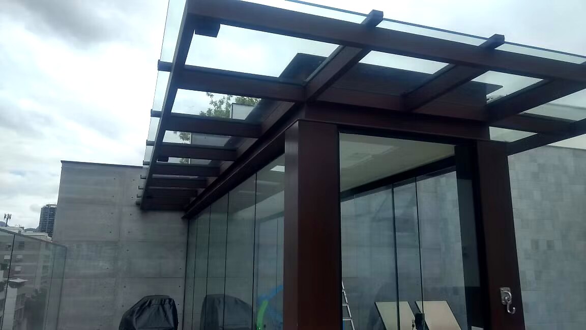Pergolado em madeira nobre com cobertura em vidro sobre varanda de cobertura urbana