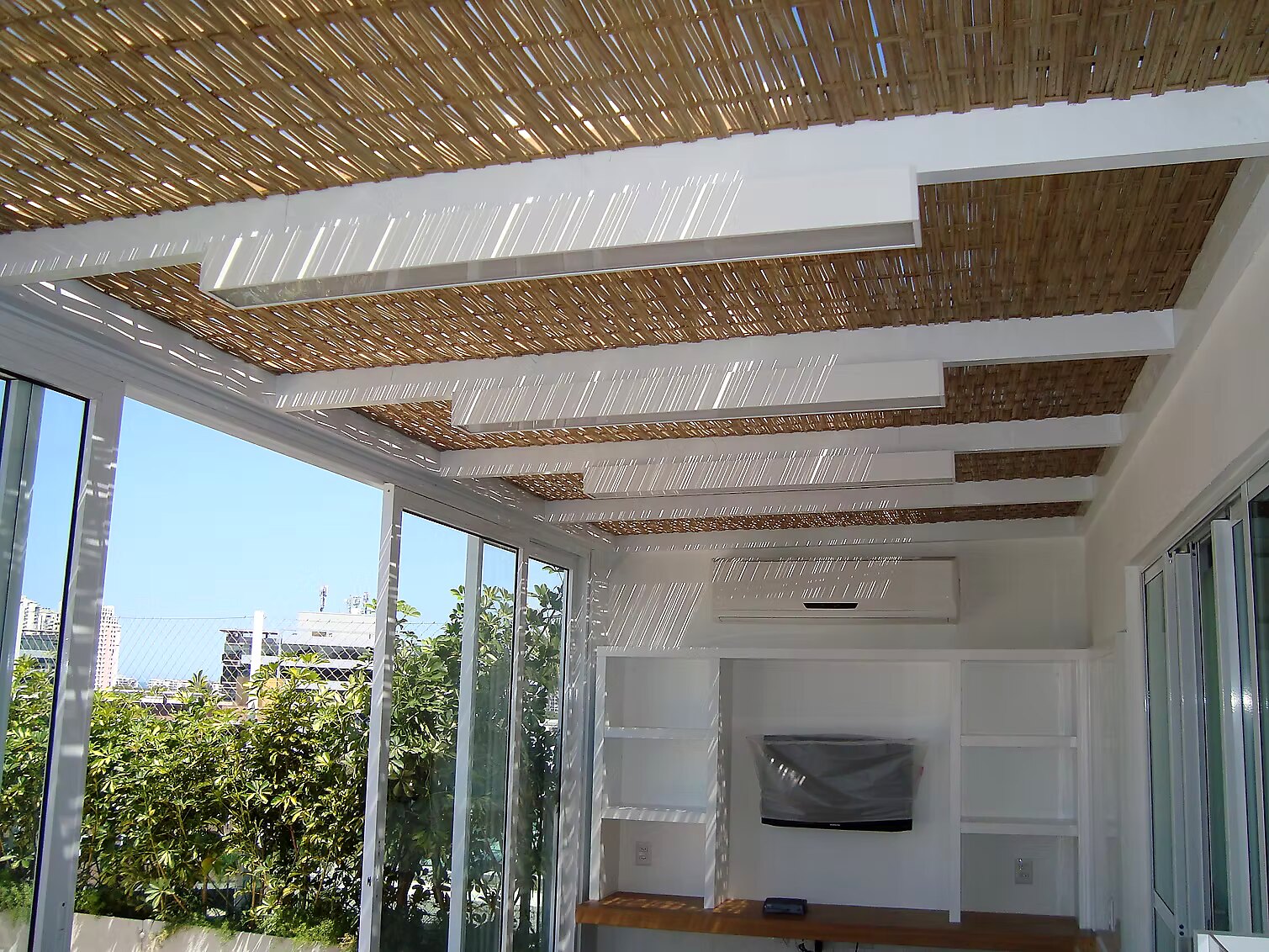 Pergolado em alumínio branco com fechamento em bambu sobre área gourmet residencial