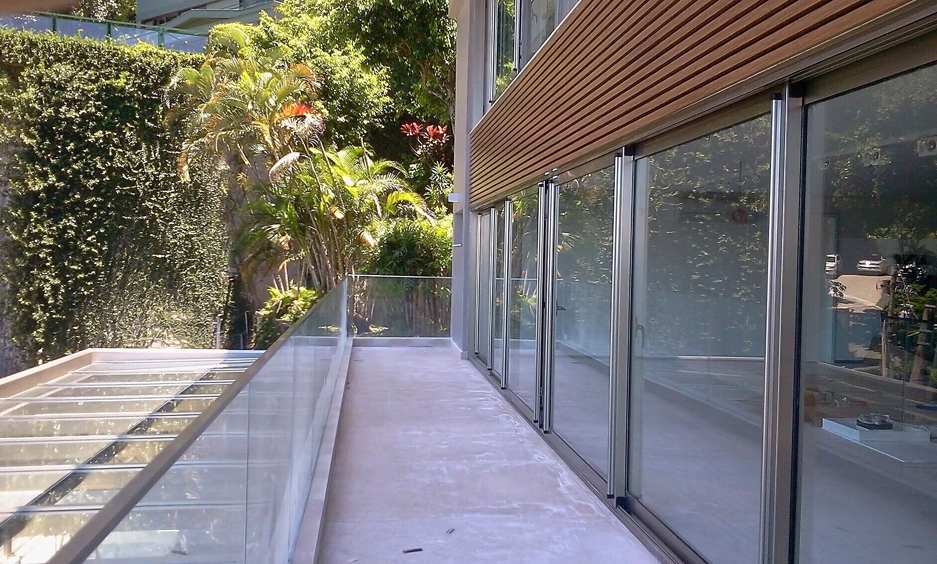 Sistema de portas acústicas de correr em varanda residencial com vista para jardim tropical
